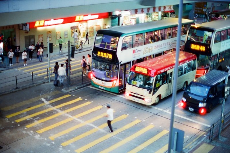 man crossing on pedestrian lane near different vehicles on road during daytime