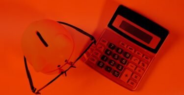 A piggy bank and calculator on an orange background.