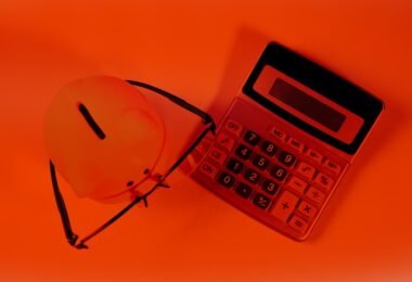 A piggy bank and calculator on an orange background.